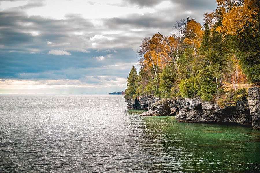 Contact Us - Fall Scene in Wisconsin, a Rocky Cliff Overlooking a Lake, Trees Turning Gold and Orange