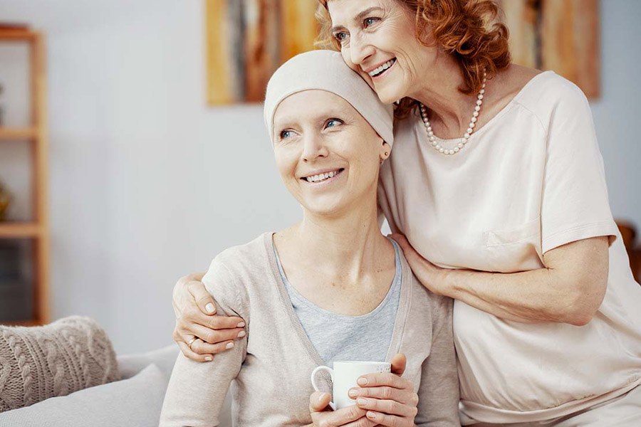 Critical Illness Insurance - Two Woman Staying Positive and Sitting Together at Home Enjoying Their Time Together after a Successful Radiation Therapy Session