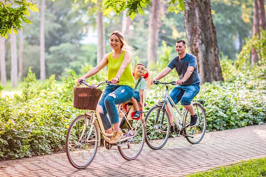 Employee Benefits - Happy Family Riding Bikes Together Outdoors on a Summer Day